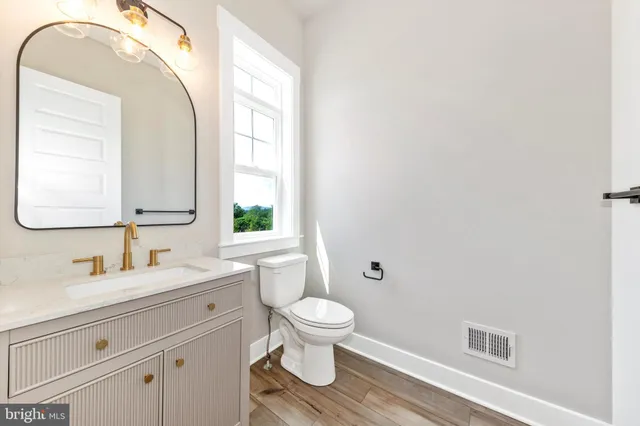 a bathroom with a granite countertop sink a toilet and a mirror