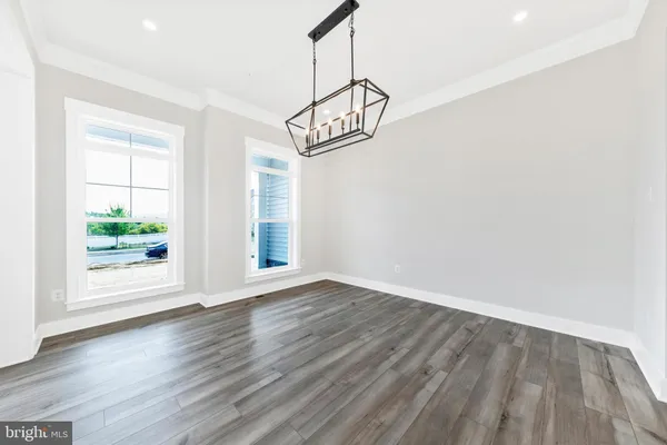 a view of an empty room with wooden floor and windows