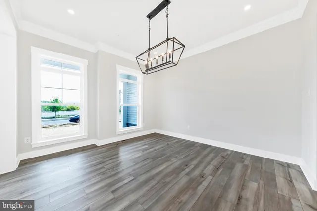 a view of an empty room with wooden floor and windows