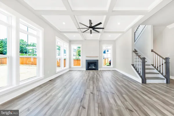 an empty room with wooden floor fan a fireplace and windows