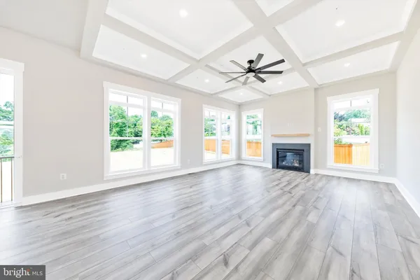 an empty room with windows fireplace and a ceiling fan
