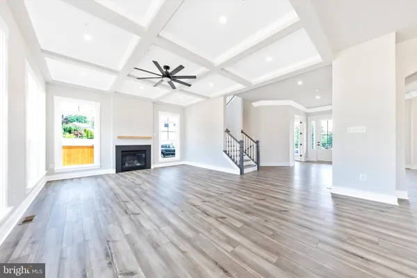 a view of a livingroom with a fireplace a ceiling fan and wooden floor