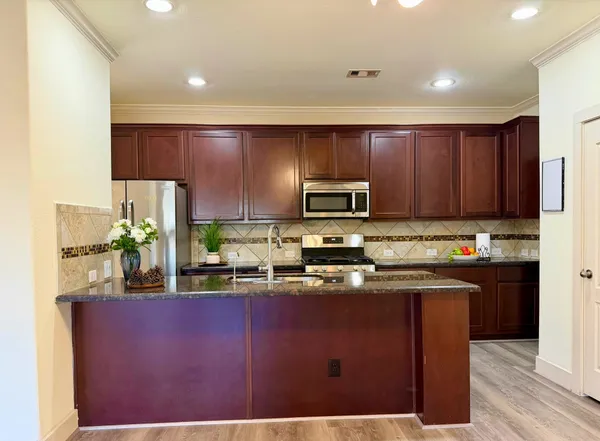 a kitchen with kitchen island granite countertop a sink cabinets and stainless steel appliances