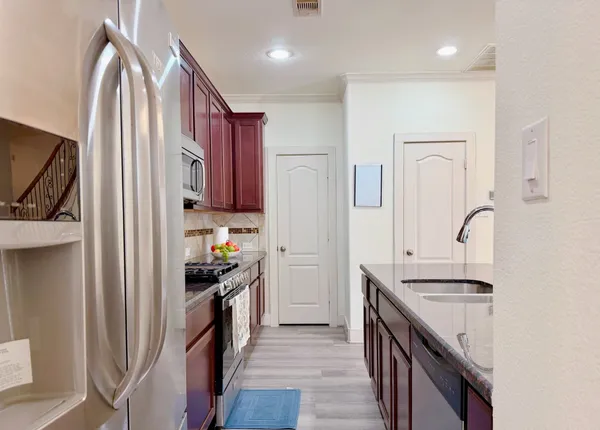 a kitchen with stainless steel appliances granite countertop a refrigerator a stove and a sink with wooden floor