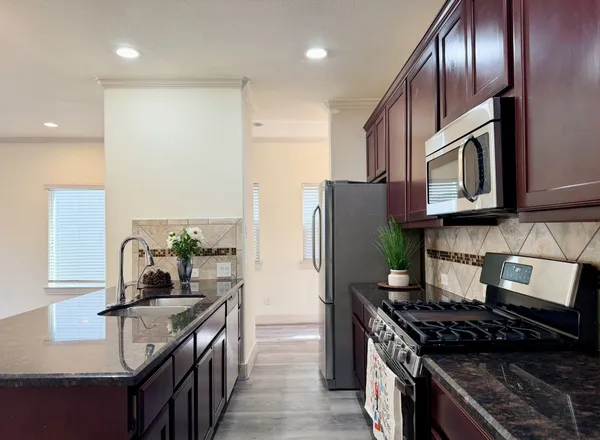 a kitchen with stainless steel appliances granite countertop a stove top oven a sink and dishwasher