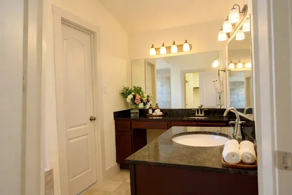 a bathroom with a granite countertop sink a mirror and a bathtub