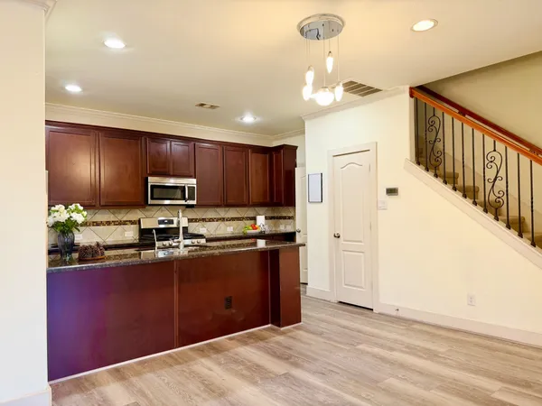 a kitchen with stainless steel appliances granite countertop a refrigerator a stove top oven a sink dishwasher and wooden cabinets