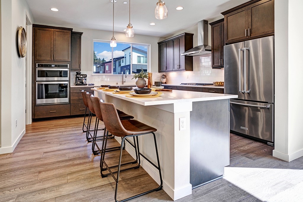 518 238th Street Southeast, Unit A Bothell, WA 98021 - Photo 7 of 31 a kitchen with stainless steel appliances a refrigerator a stove a sink and a dining table with wooden floor