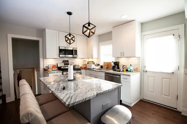 a kitchen with granite countertop cabinets a stove a sink and a chandelier