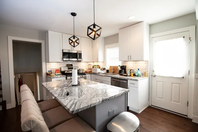 a kitchen with granite countertop cabinets a stove a sink and a chandelier