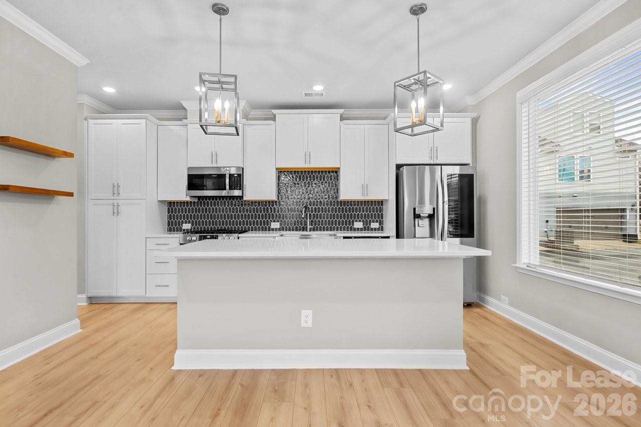 1515 Hidden Falls Road Charlotte, NC 28206 - Photo 11 of 35 a large kitchen with stainless steel appliances a large counter top a refrigerator a sink dishwasher a kitchen island a stove and a wooden floor