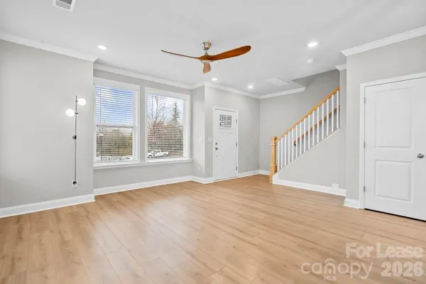a view of an empty room with a window and wooden floor