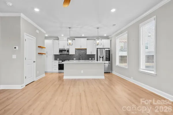 a large white kitchen with kitchen island a sink a center island stainless steel appliances and a window