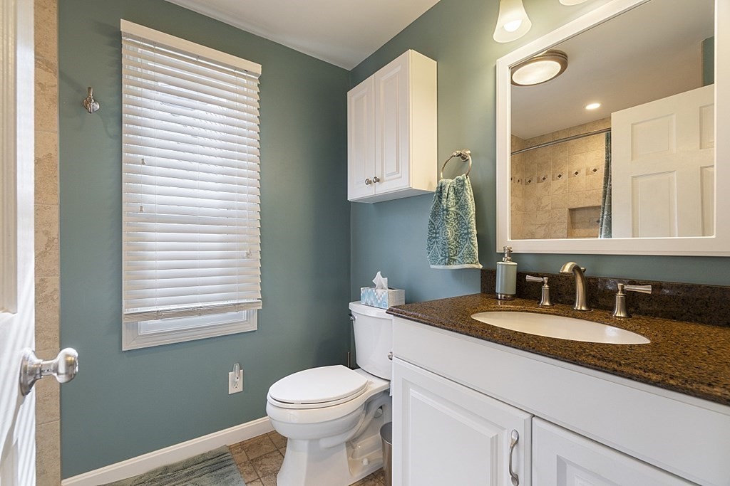 1541 Middlesex Street, Unit 16 Lowell, MA 01851 - Photo 8 of 29 a bathroom with a granite countertop sink toilet and mirror