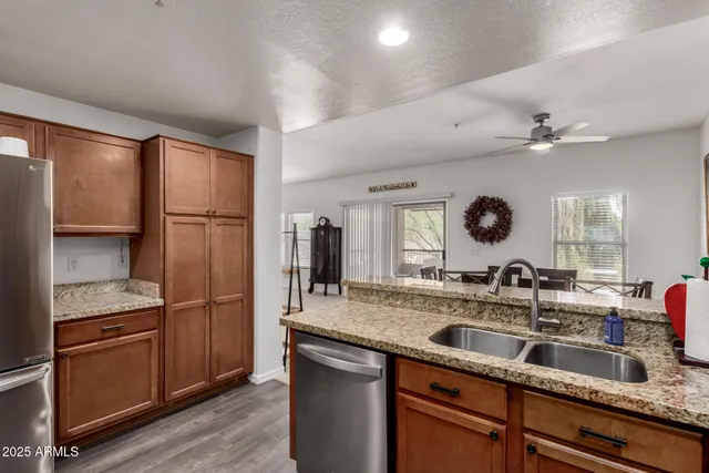 a kitchen with stainless steel appliances granite countertop a stove top oven a sink dishwasher a dining table and chairs with wooden floor