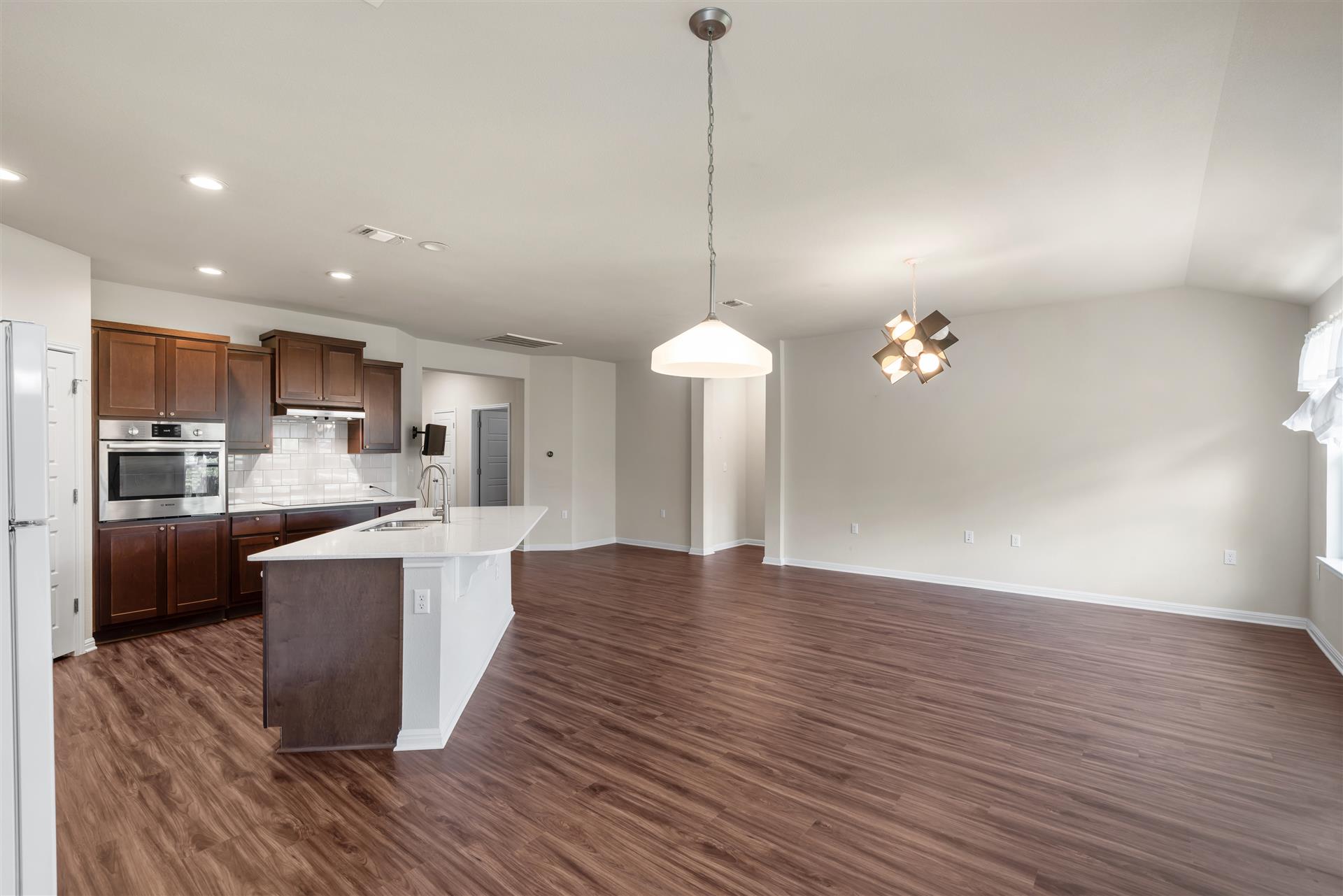 16512 Enamorado Road Manor, TX 78653 - Photo 25 of 31 A well-lit, open-concept kitchen and living area with warm wood flooring invites seamless entertaining.
