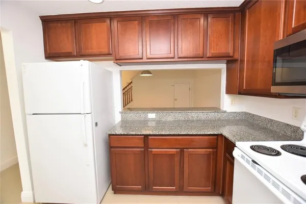 a kitchen with granite countertop a refrigerator and a stove top oven