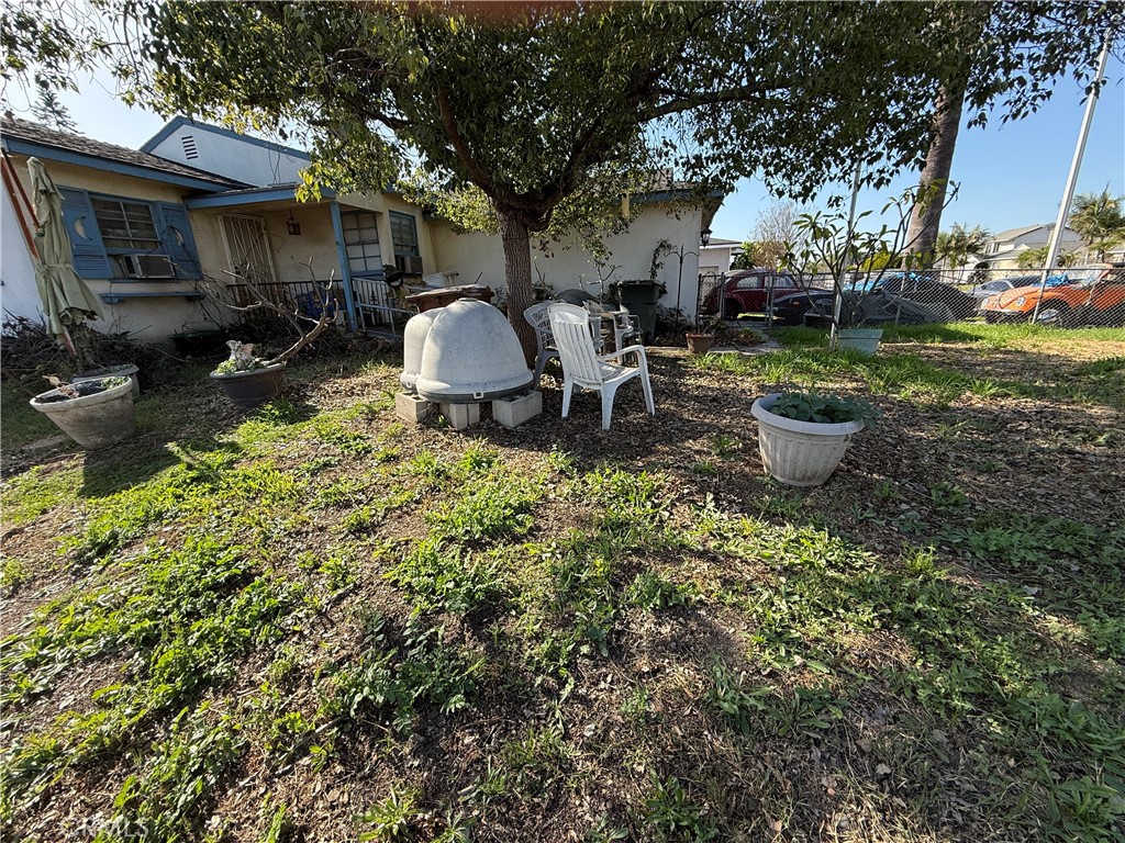 a view of a backyard with table and chairs potted plants and a large tree
