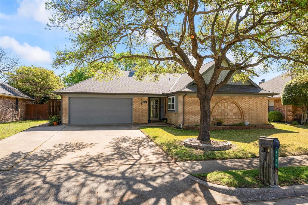 View of front facade featuring a garage, brick siding, fence, and a front lawn