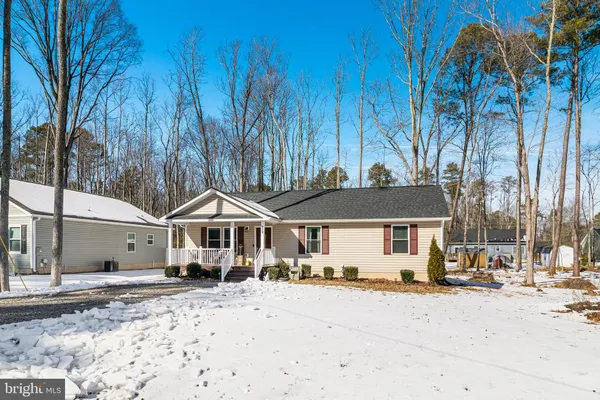 a front view of a house with a yard covered with snow and trees