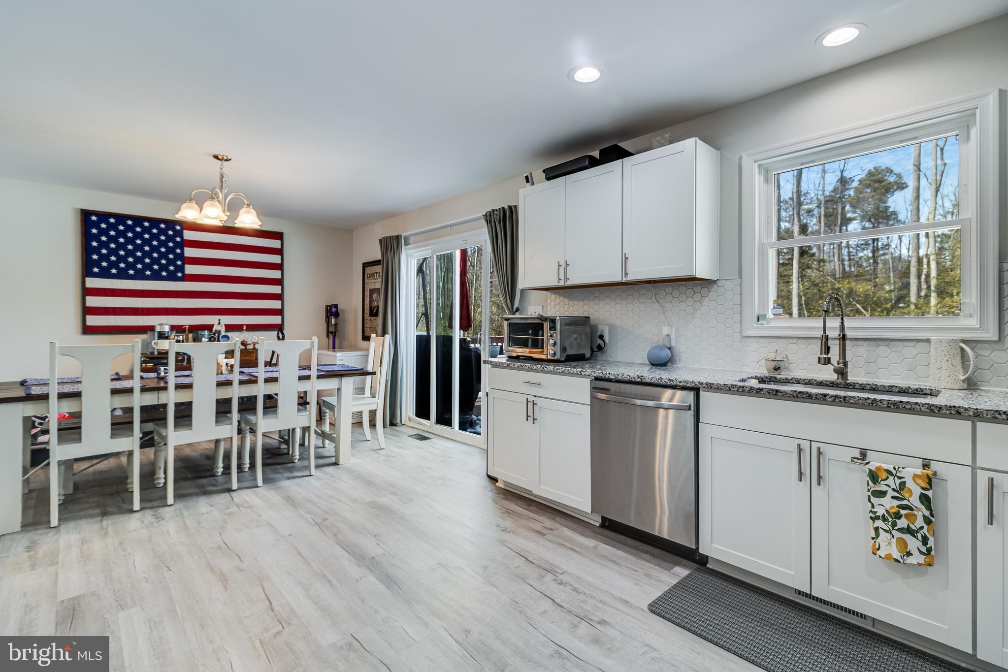 339 Azure Drive Colonial Beach, VA 22443 - Photo 10 of 28 a kitchen with stainless steel appliances granite countertop a stove top oven a sink a dining table and chairs with wooden floor