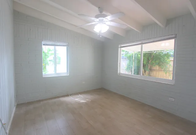 an empty room with windows and chandelier fan