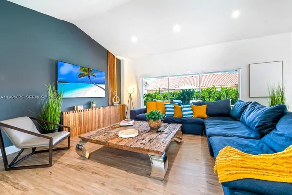 a living room with furniture kitchen view and a large window