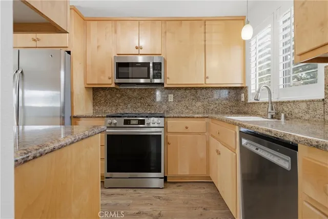 a kitchen with stainless steel appliances granite countertop a sink stove and refrigerator
