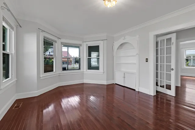 a view of an empty room with wooden floor and a window