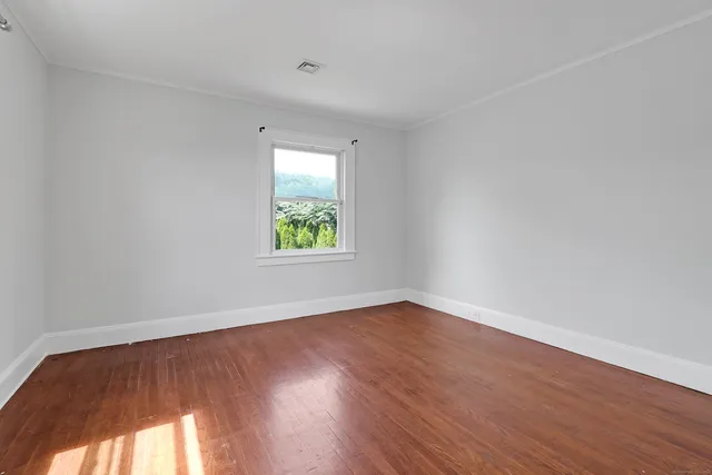 an empty room with wooden floor and window