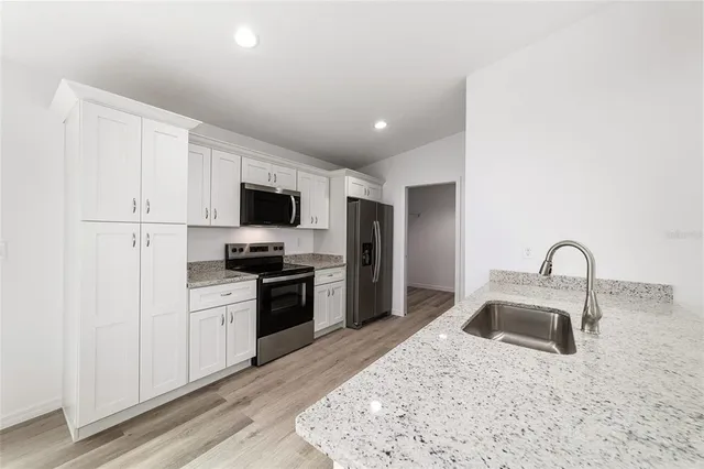 a kitchen with a sink stainless steel appliances and white cabinets