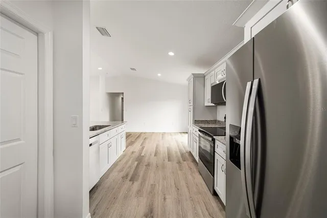 a kitchen with stainless steel appliances granite countertop a refrigerator and a stove top oven