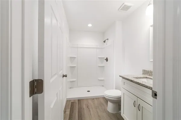 a bathroom with a granite countertop sink a toilet and shower