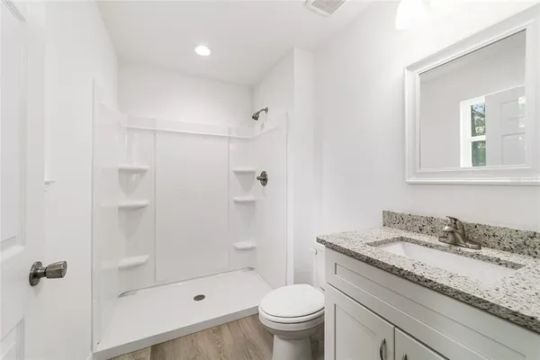 a bathroom with a granite countertop sink a toilet and shower