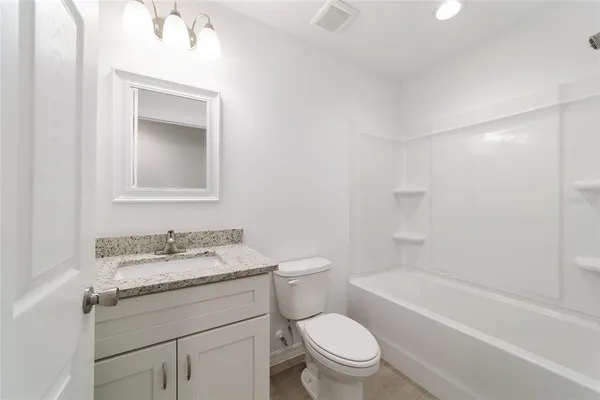 a bathroom with a granite countertop sink a toilet and bathtub