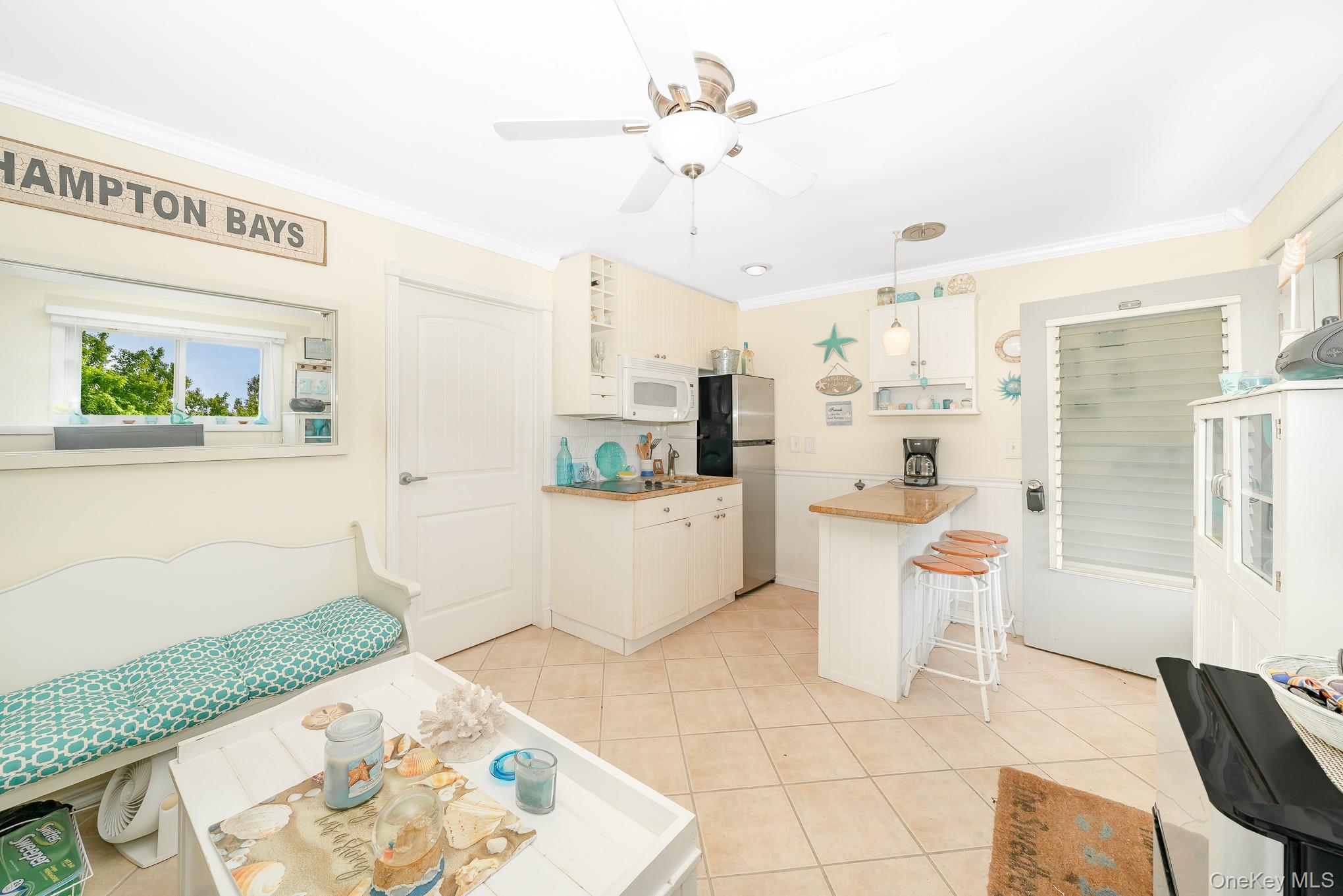 50 Rampasture Road, Unit 6 Hampton Bays, NY 11946 - Photo 25 of 35 a white kitchen with a sink a stove a dining table and chairs