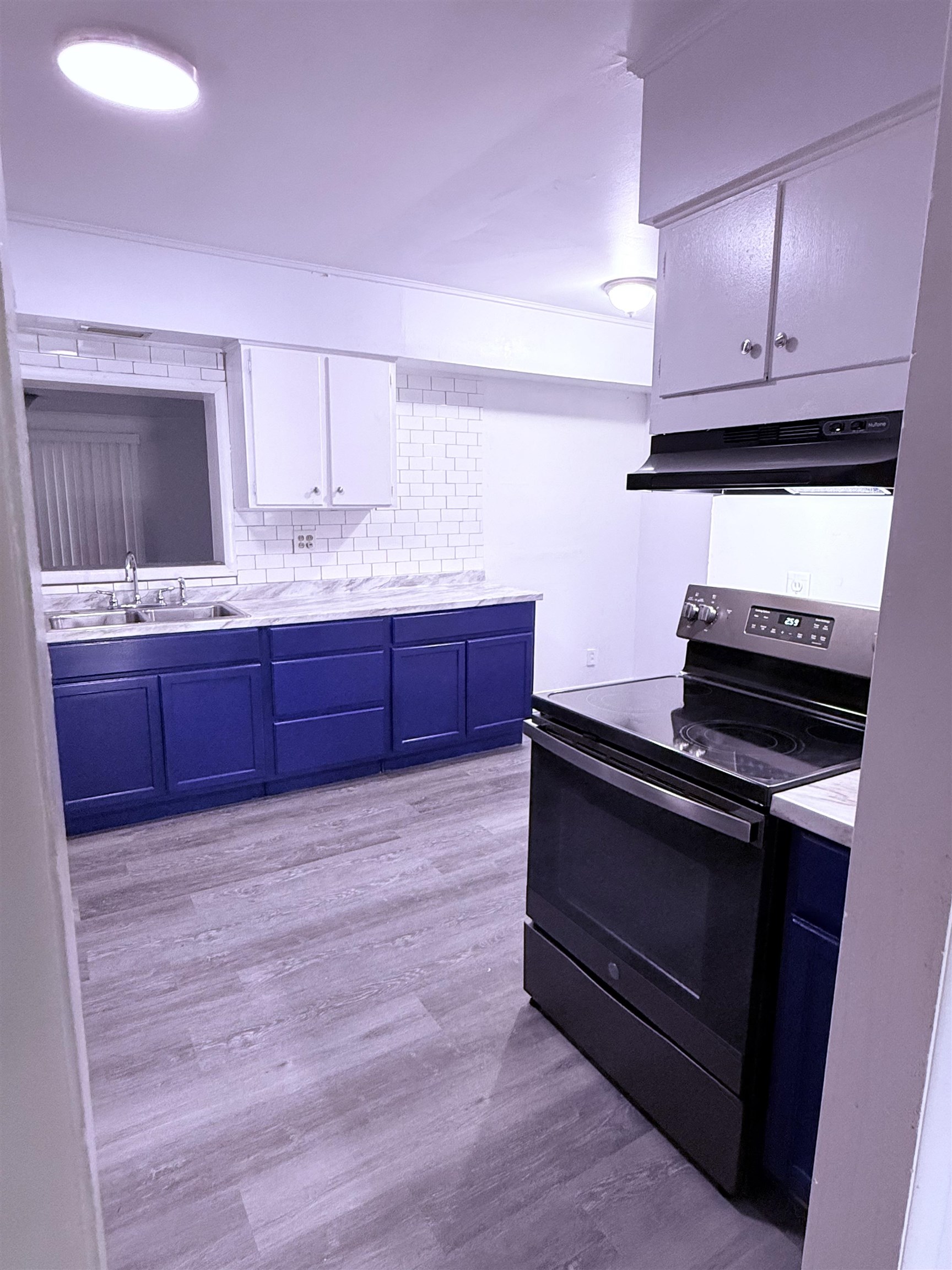 4089 Tessland Road Memphis, TN 38128 - Photo 8 of 34 Kitchen with electric range oven, under cabinet range hood, blue cabinetry, light countertops, and white cabinets
