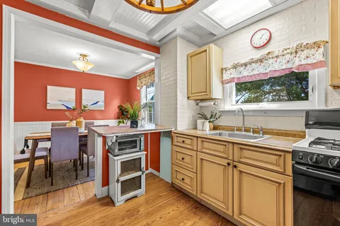 a kitchen with stainless steel appliances a stove a sink and a dining table with wooden floor