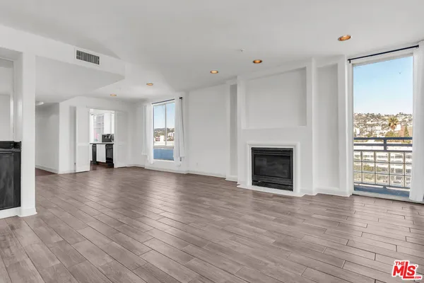 a view of an empty room with wooden floor and a fireplace