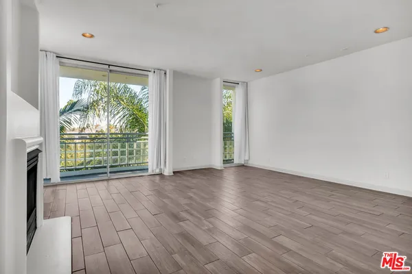 an empty room with wooden floor fireplace and windows