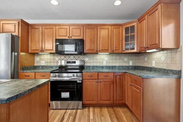 a kitchen with stainless steel appliances granite countertop wooden cabinets stove top oven and sink