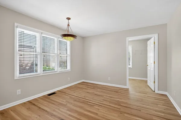 a big room with wooden floor a chandelier and windows
