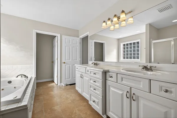 a spacious bathroom with a granite countertop double vanity sink mirror and bathtub
