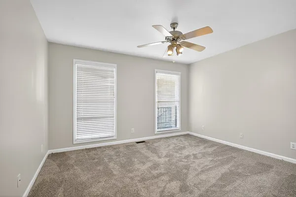 an empty room with windows and fan