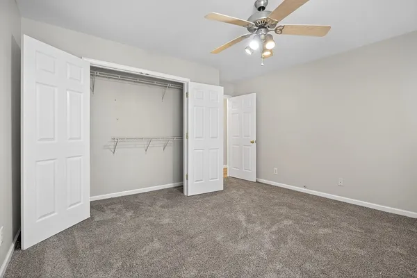an empty room with closet and a ceiling fan