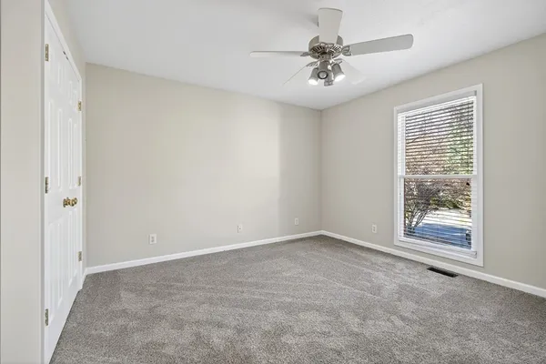 an empty room with windows and fan