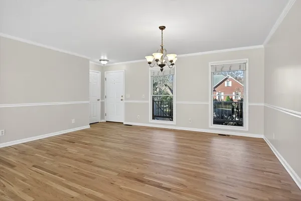 an empty room with wooden floor mirror and windows