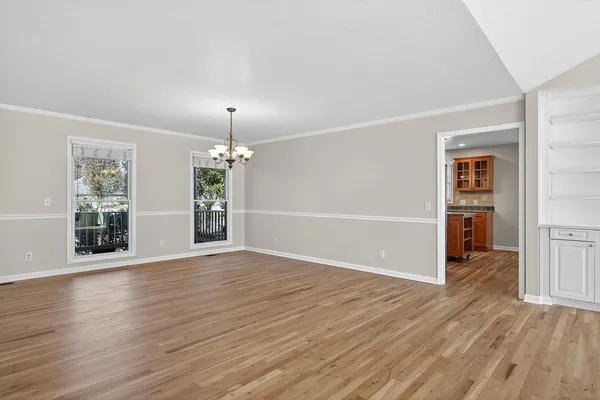 an empty room with wooden floor cabinet and windows