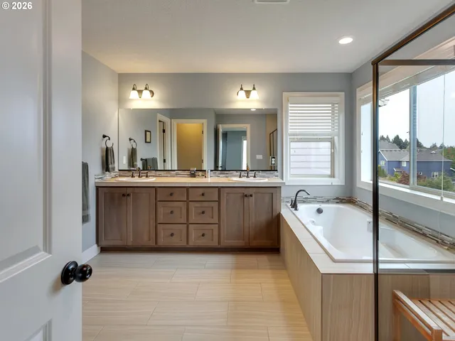 a bathroom with a tub a double vanity sink a mirror a window and a bathtub