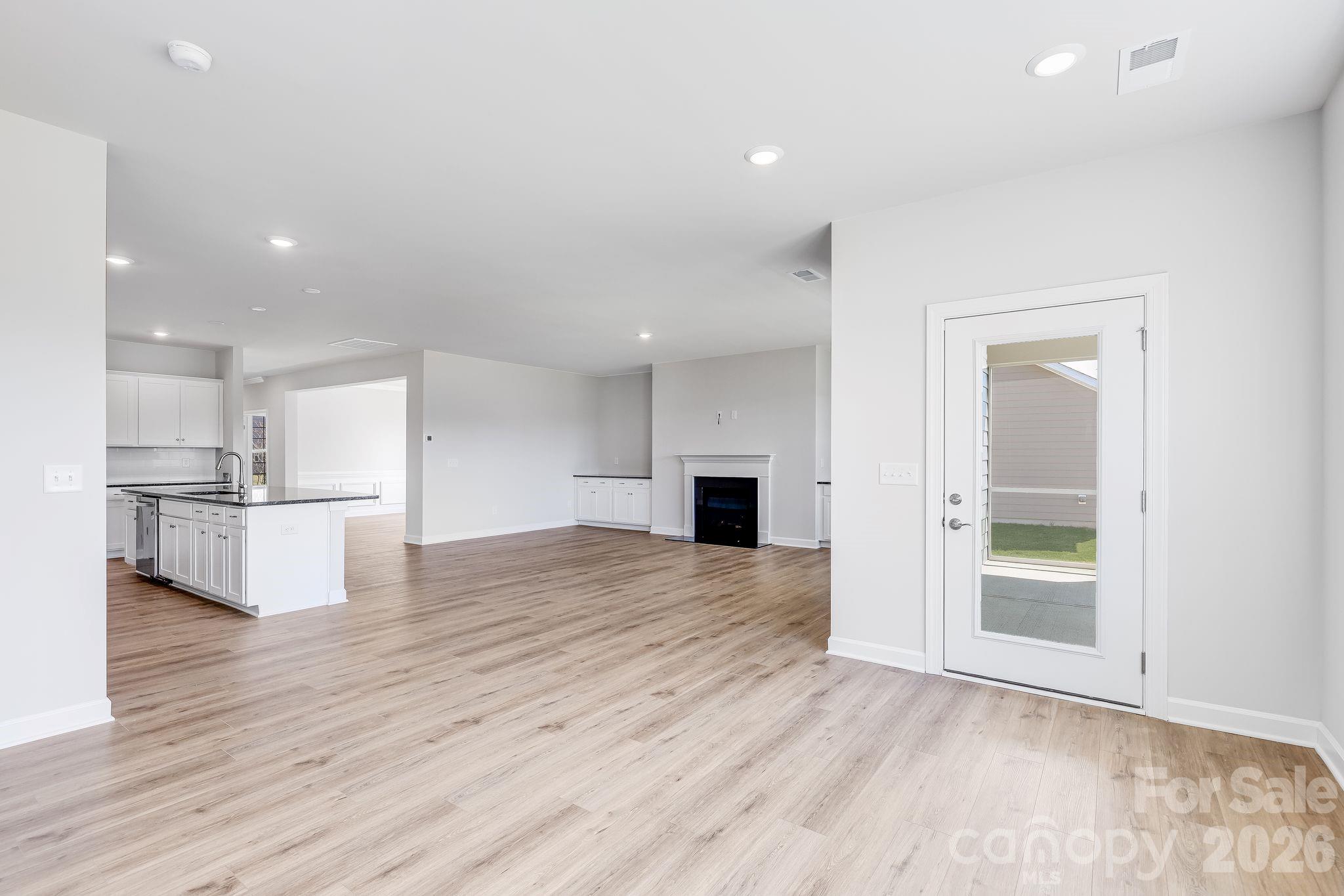 2287 Moon Crst Road, Unit 143 Lancaster, SC 29720 - Photo 10 of 35 an empty room with wooden floor and a kitchen view